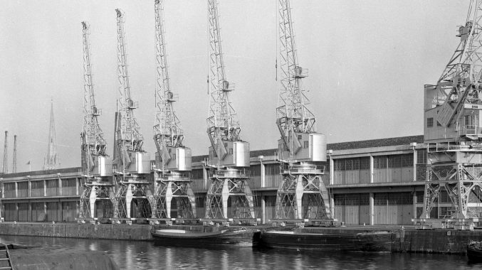 black and white photo of 4 cargo cranes