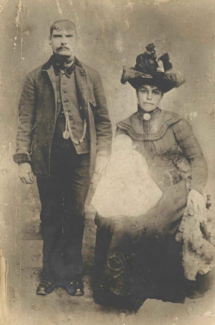 sepia portrait of a man and woman with a baby on her lap